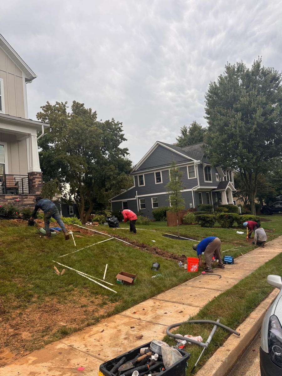 Crew laying out sprinkler zones with string lines across a front yard